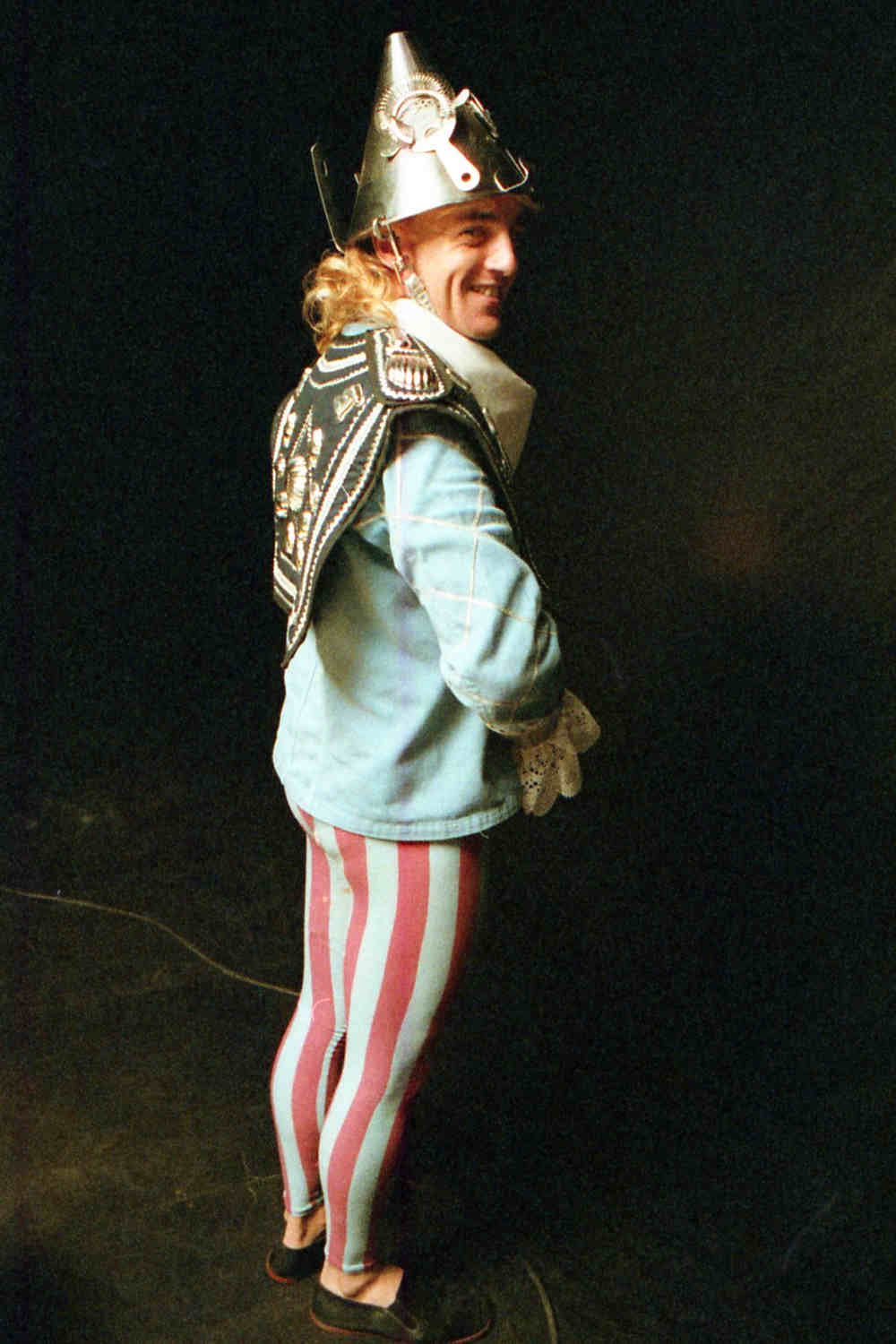 Handspan Theatre Guts costumed actor wearing blue and silver jacket, striped blue and purple tights and silver colander helmet