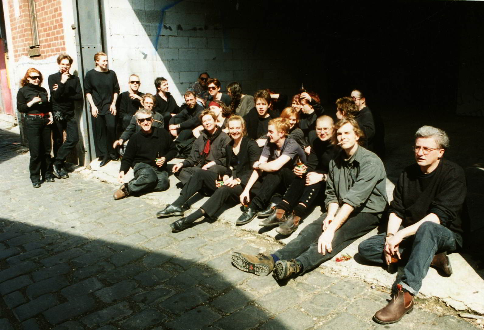 Held on the Breath of the Wind Handspan Theatre group portrait of performers sitting in a cobbled laneway
