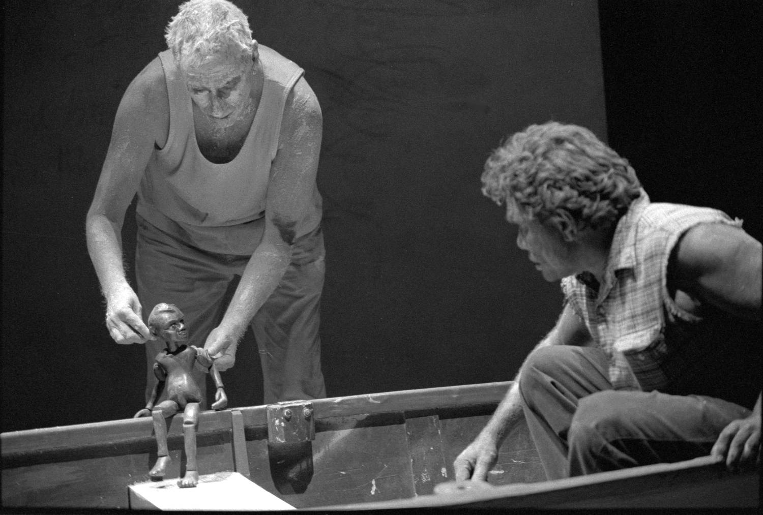 Lift Em Up Socks Handspan Theatre Puppeteer operating boy puppet conversing with Aboriginal man in dinghy. black and white