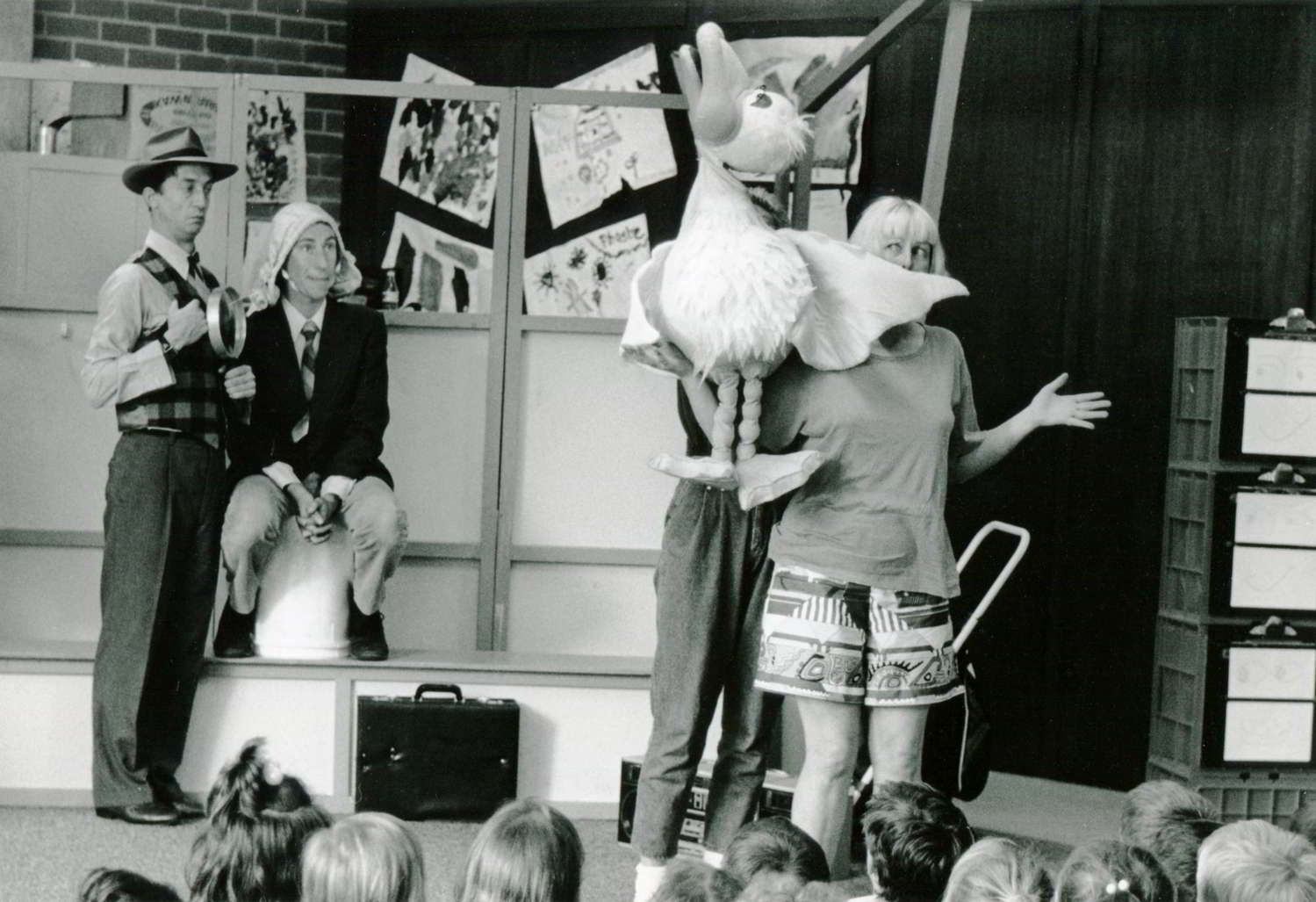 Handspan Theatre Out for A Duck actors on stage in a classroom with puppet duck, head held high, quacking