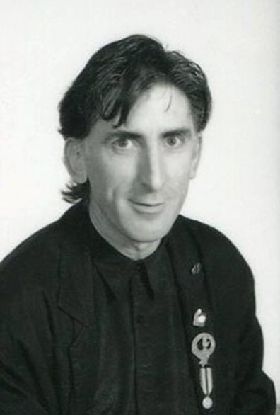Ken Evans Handspan Theatre black and white portrait of man with badge on jacket lapel