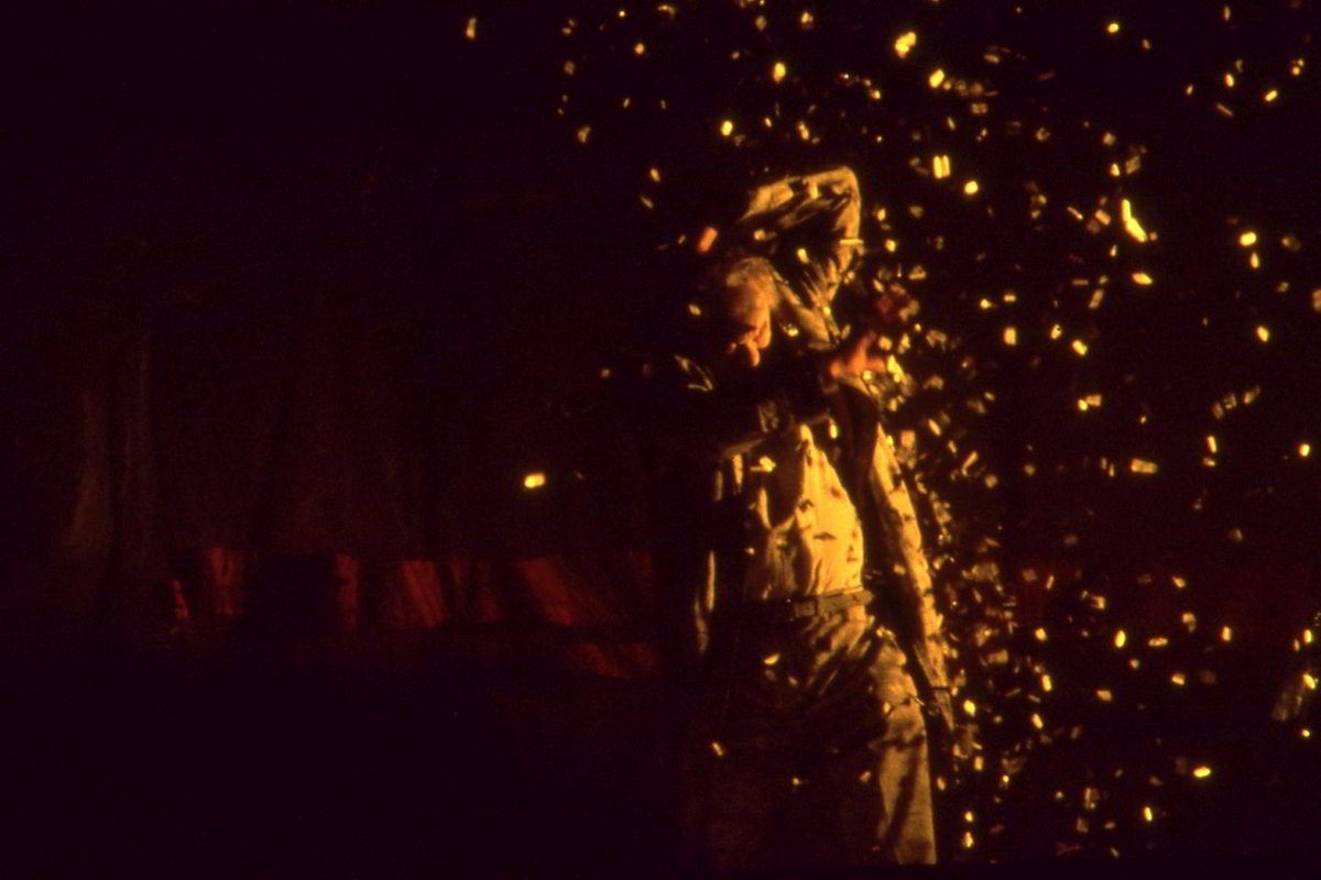 Handspan Visual Theatre Raised By Wolves a man writhing in a shower of yellow sparks pinpointed by light