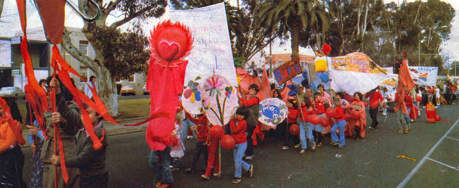lStreet Parade Mildura street children wearing  red clothing and carrying red parade puppets, objects and signs