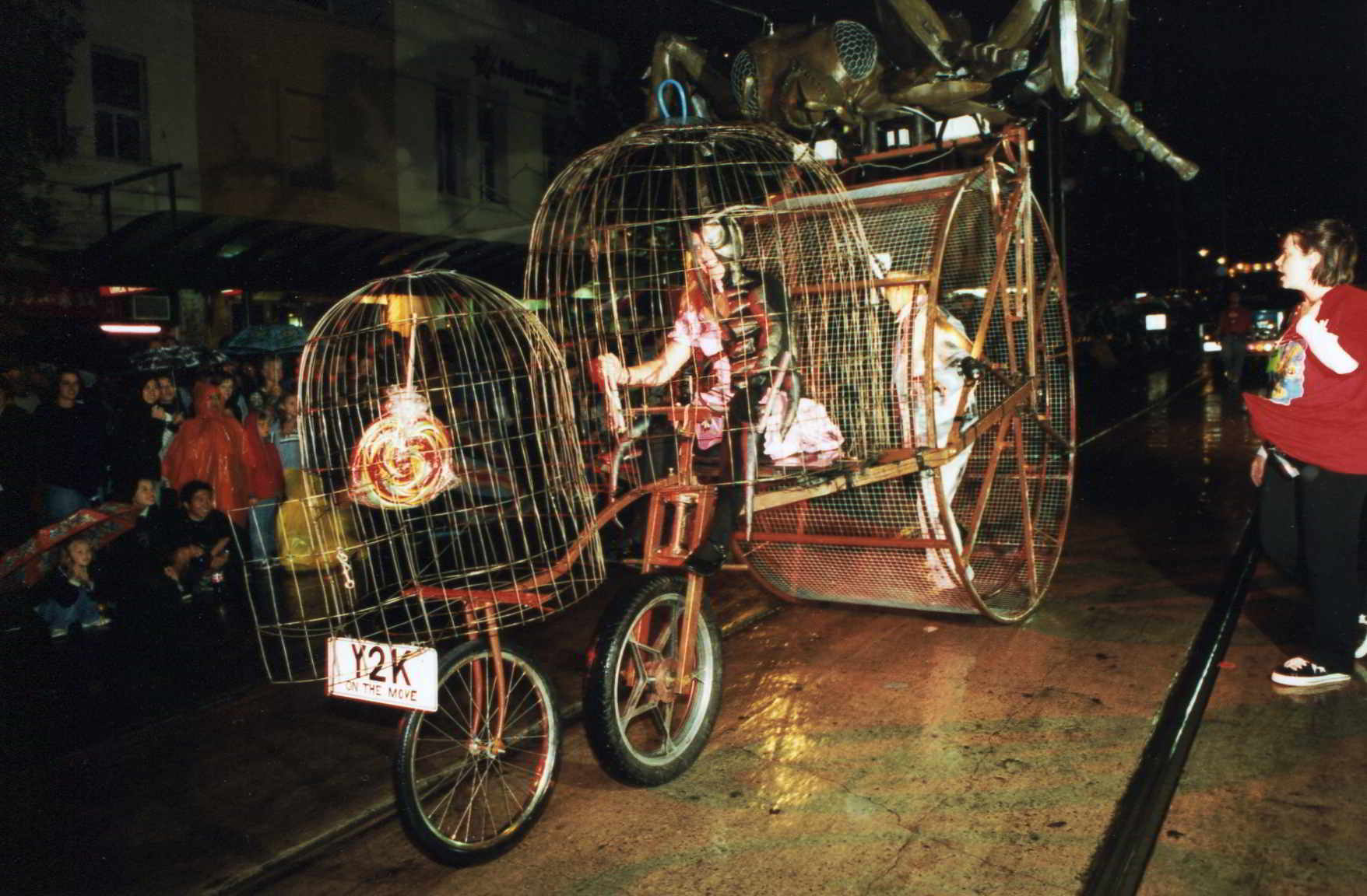 Road Roach's 3 cage parade contraption on the street at night