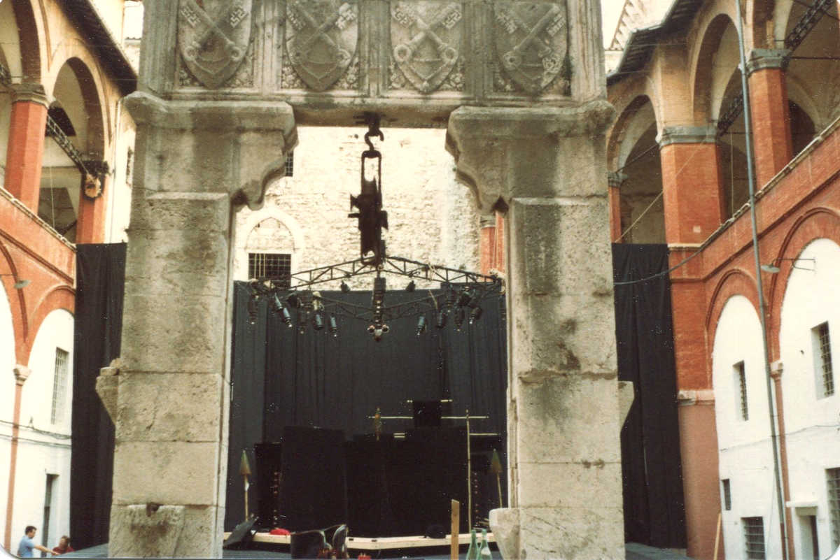 Handspan Theatre Secrets at Cortile della Rocca Carved stone arch and beyond it a demountable stage hung with black curtains