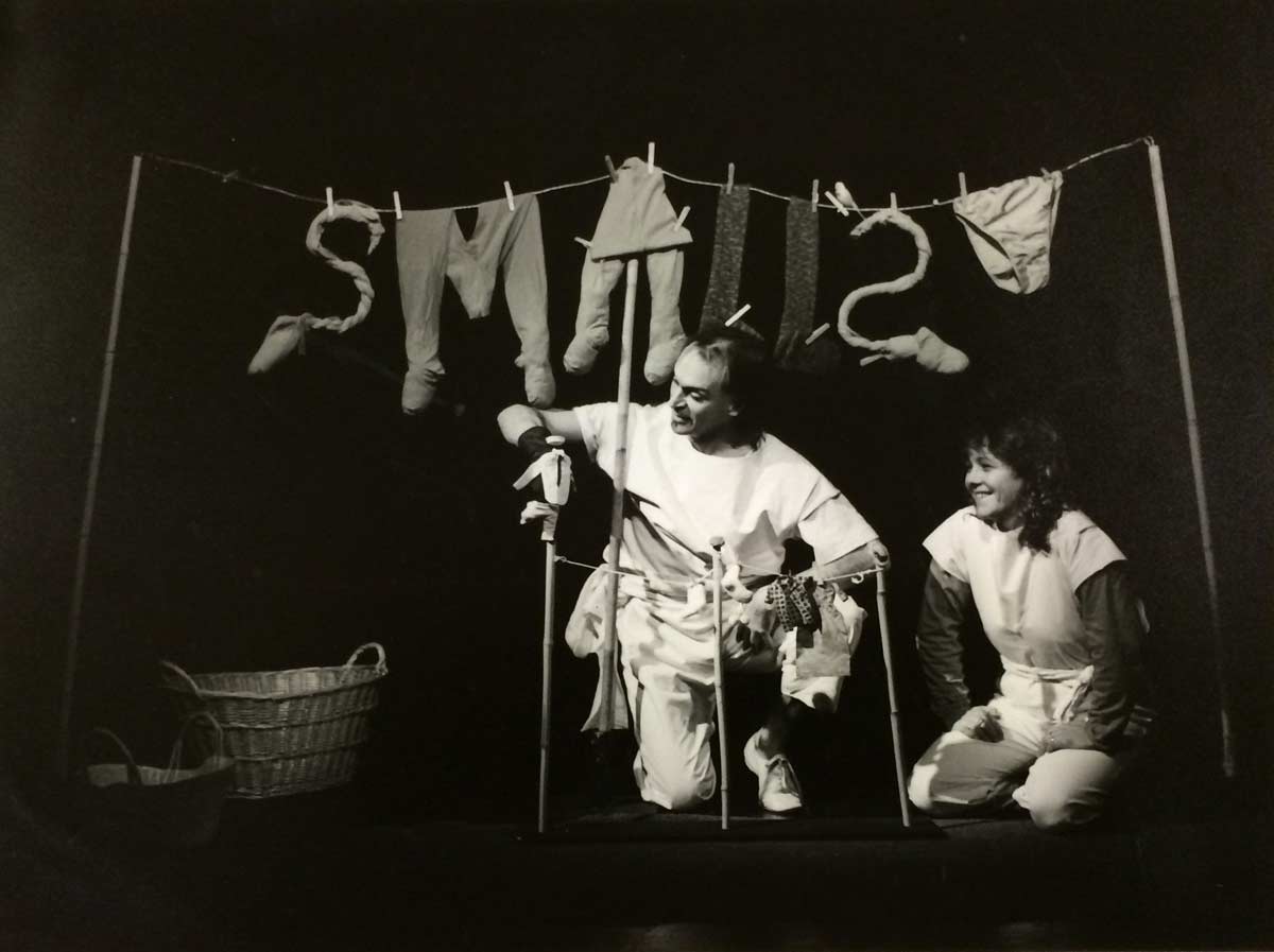 SMALLS, Handspan Theatre a man and woman with miniature clothesline in front of larger version with hanging articles making the word smalls