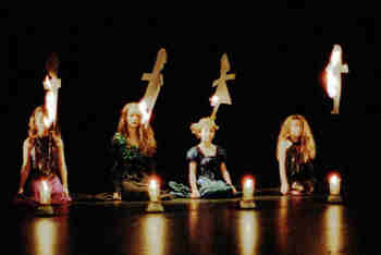 four girls watch as paper dolls, lit from candles, burn away