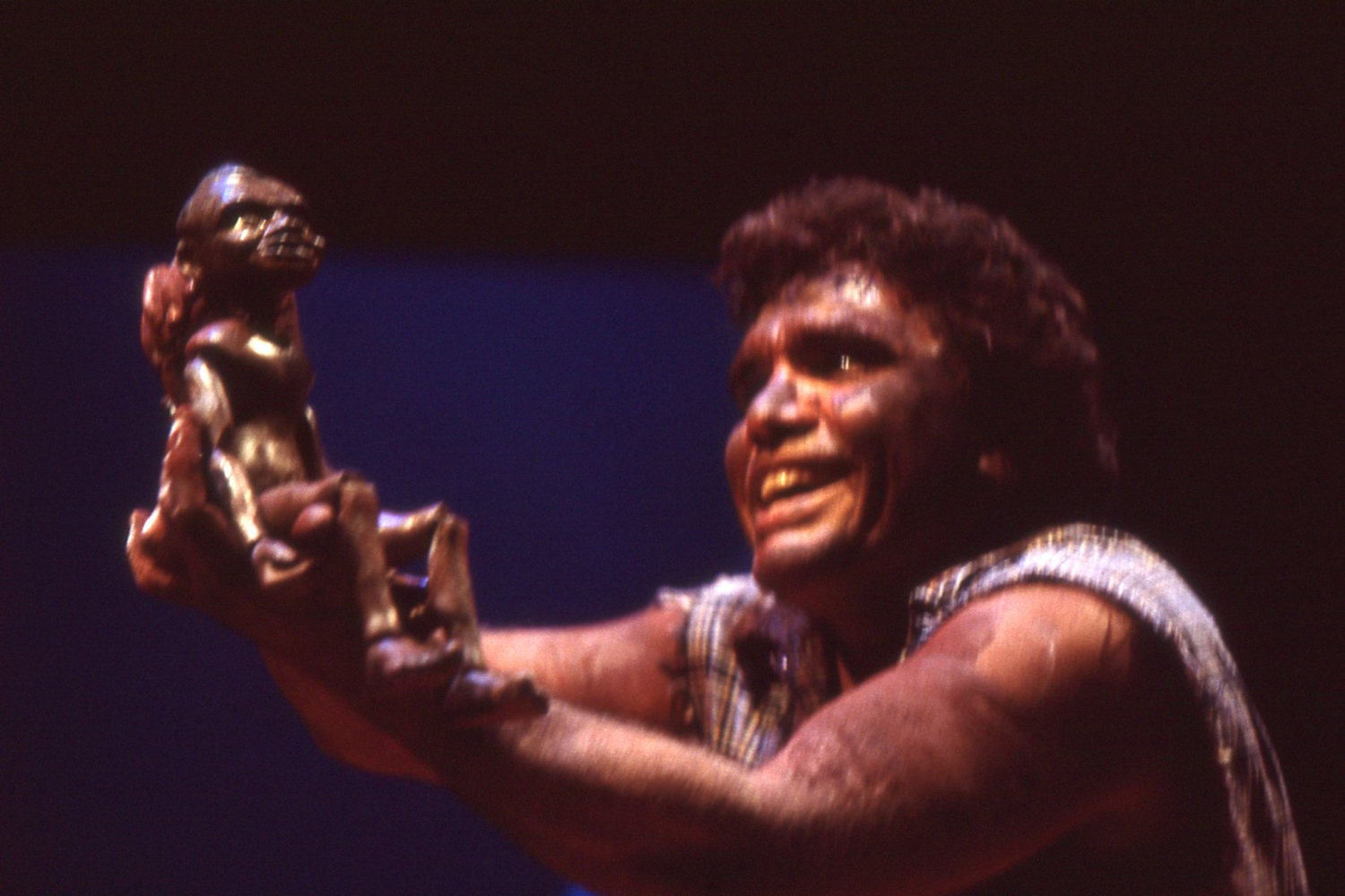 Aboriginal actor with joyful expression holding up rod puppet Aboriginal boy 