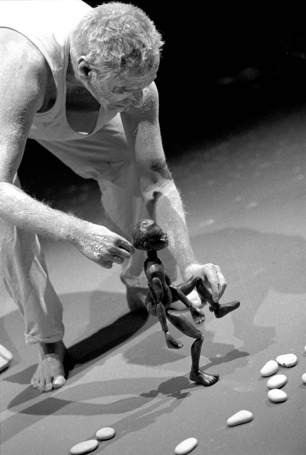 Lift 'Em Up Socks, handspan Theatre Rod Primrose, puppeteer leaning down to operate Aboriginal boy rod puppet within a stone pattern on the floor