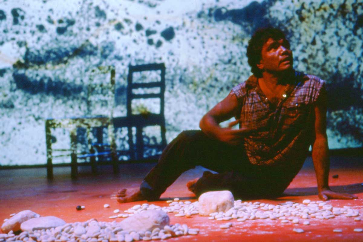 Lift 'Em Up Socks Handspan Theatre Aboriginal man sitting on the floor against a blue dot painted backdrop