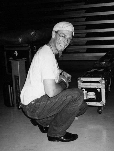 Paul Judd Handspan Theatre man with whispy beard squatting in front of road cases