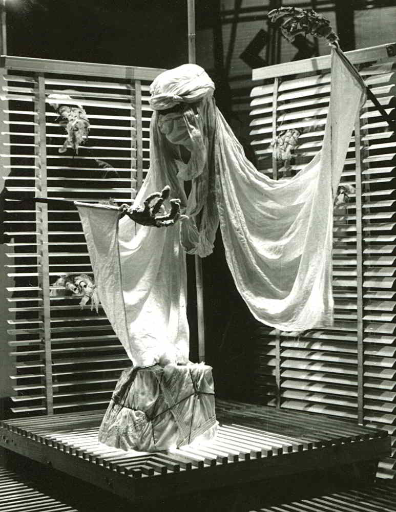 Secrets Handspan Theatre head and arms in arabic robes float above a parcel in front of walls hung with venetian blinds