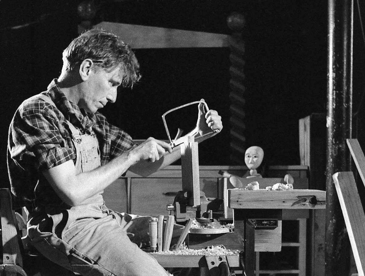 The Wooden Child Handspan Theatre man at a carpenter's bench, wooden puppet peeping out of open drawer