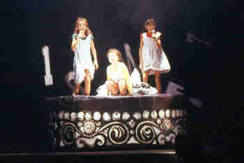 three girls chatting and laughing on a round couch decorated like a cake
