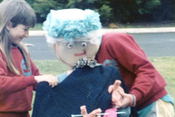 children holding their life-size puppet old lady with knitting