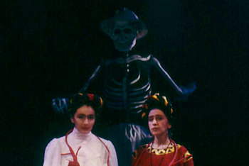 two women seated as before, with large skeleton looming behind them